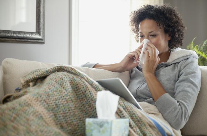 a lady sitting on the couch blowing her nose