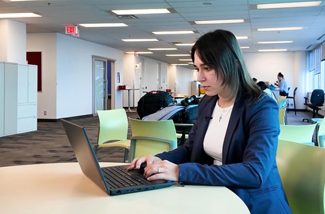 Nicole, summer student typing on laptop in lounge
