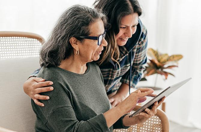 elderly parent and daughter looking at tablet together