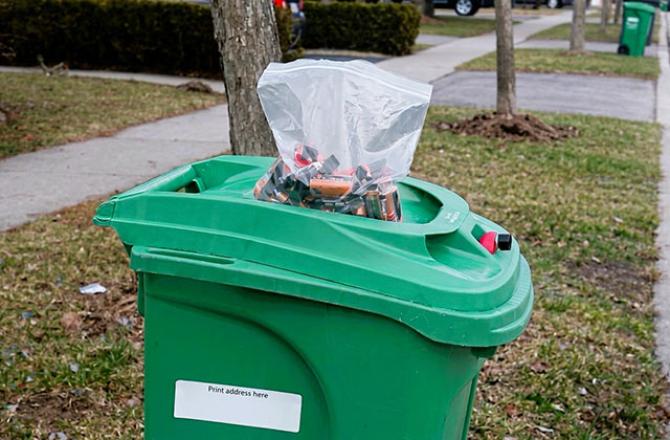 green bin with bag of batteries on top 