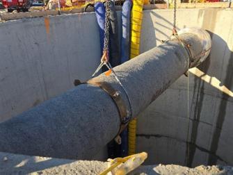 New sanitary sewer pipe being lowered into installation launch shaft.